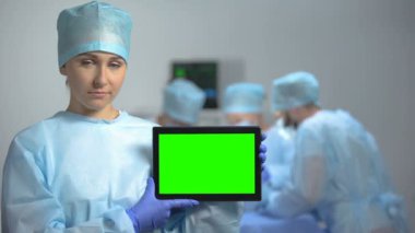 Ciddi hemşire çalışma sırasında yeşil ekran ile tablet Pc tutan, ölüm oranı