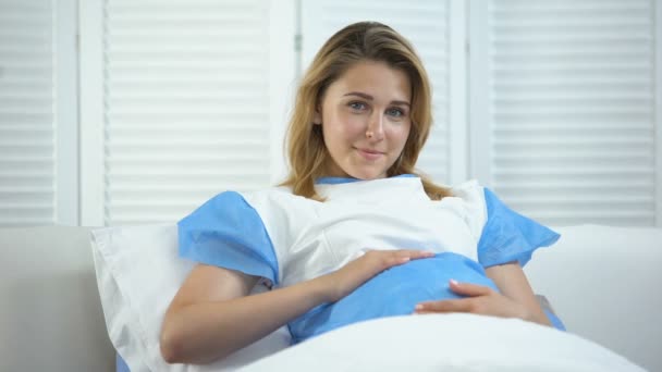 Beautiful pregnant woman holding tummy and smiling at camera, prenatal care — Stock Video