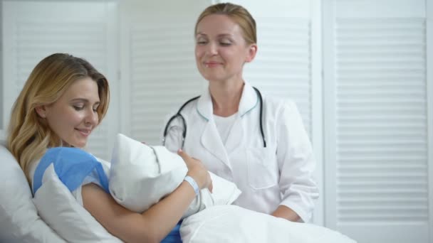 Médico y madre sosteniendo al recién nacido sonriendo a la cámara, contacto piel con piel — Vídeo de stock