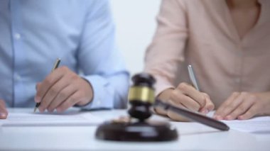 Evlilik yüzük ve toklak closeup, eşler arka planda boşanma belgesi imzalayarak