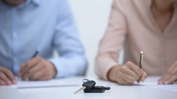 Primeros planos de las llaves del coche, pareja firmando documentos de divorcio sobre la división de propiedad — Vídeo de stock