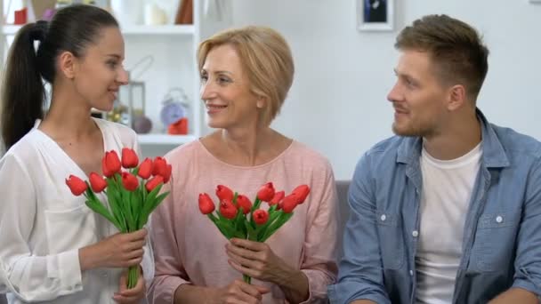 Madre e moglie anziana con mazzi di tulipani seduti vicino al maschio, sorridenti sulla macchina fotografica — Video Stock