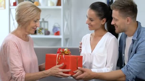 Pareja cariñosa presentando la caja de regalo a la suegra, celebrando el cumpleaños de los padres — Vídeo de stock