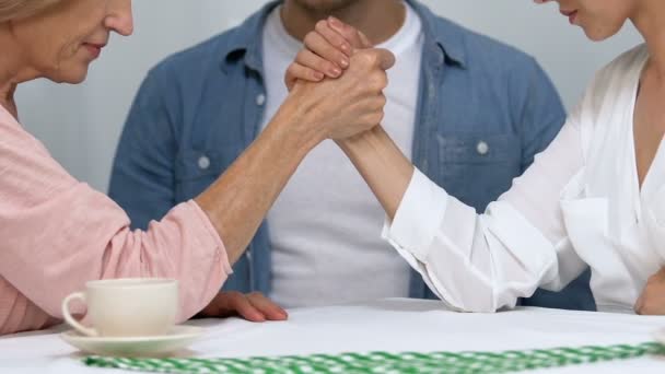 Zmatený muž pozoroval ženu a matku, jak soupeří o jeho pozornost. — Stock video