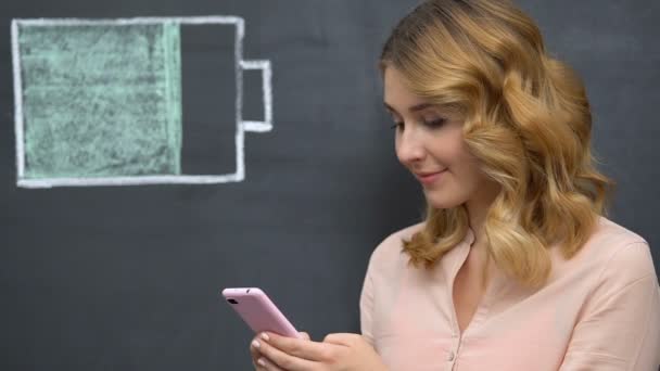 Vrouw surfen internet op mobiele telefoon, batterijsymbool getekend, energie-efficiëntie — Stockvideo