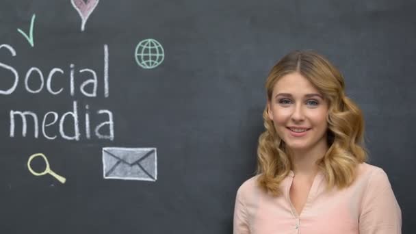 黒板、近代的な技術上のソーシャルメディアのフレーズを指す笑顔の女性 — ストック動画