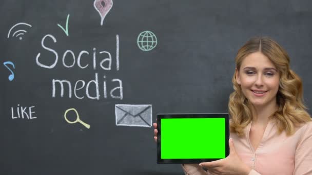 Θηλυκό που δείχνει την καρτέλα με το κλειδί που στέκεται στο φόντο του μαυροπίνακα χρησιμοποιώντας μέσα κοινωνικής δικτύωσης — Αρχείο Βίντεο