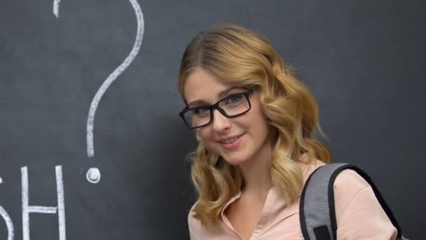 Estudiante con gafas sosteniendo libros, hablas inglés en pizarra, educación — Vídeo de stock