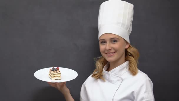 Senhora cozinheiro atraente demonstrando bolo apetitoso no prato, culinária e padaria — Vídeo de Stock