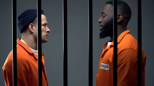 Prisioneiros afro-americanos e caucasianos olhando uns para os outros na cela, conflito — Fotografia de Stock