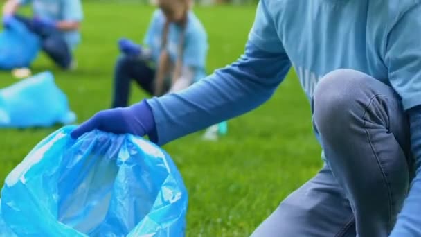 Волонтерська команда в рукавичках збирає сміття в парку, охорона природи, екологія — стокове відео