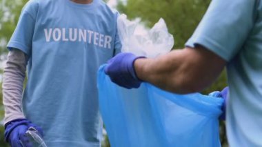 Mutlu küçük gönüllü çöp torbasına plastik çöp koyarak, şehir parkı temizlik