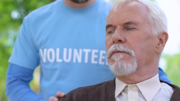 Турбота про чоловіка-добровольця, який розмовляє зі старим самотнім чоловіком під час прогулянки в парку, допомога — стокове відео