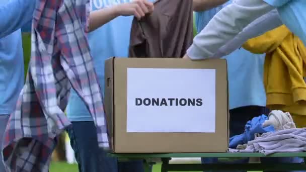 Grupo de voluntarios poniendo ropa en la caja de donaciones, orfanato ayuda proyecto de caridad — Vídeos de Stock