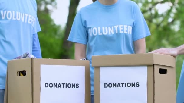 Χαμογελαστοί εθελοντές δίνοντας ψηλά πέντε κουτιά δωρεών υπαίθρια, φιλανθρωπικό έργο — Αρχείο Βίντεο