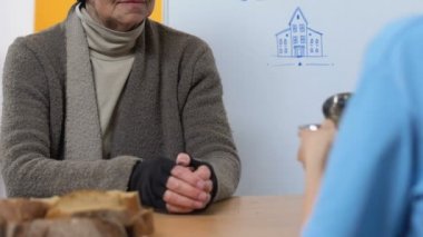 Gönüllü merkezinde yiyecek kabul eden yaşlı evsiz kadın, sosyal güvensizlik, yardım
