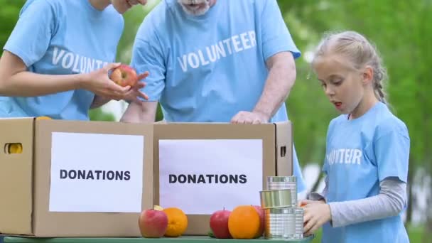 Pequeña niña voluntaria poniendo productos alimenticios en la caja de donación concepto de filantropía — Vídeo de stock