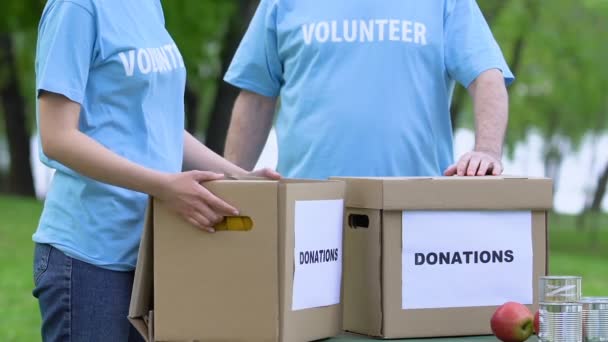 Dua relawan memegang kotak sumbangan, misi kemanusiaan, konsep amal, bantuan — Stok Video