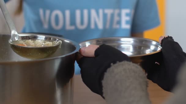 Volunteer pouring soup for homeless person in social support center, assistance — Stock Video