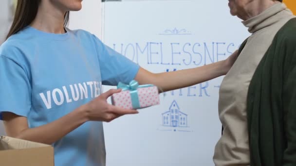 Φιλική γυναίκα εθελόντρια που παρουσιάζει κουτί δώρου για την φτωχή γυναίκα στο φιλανθρωπικό κέντρο — Αρχείο Βίντεο