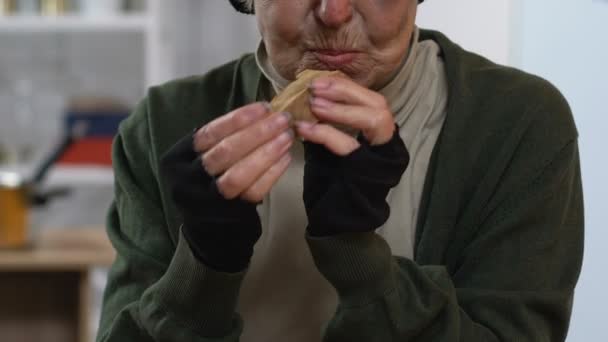 Senior bezdomnych Pani jedzenia kawałek chleba z drżenie rąk, osoby o niskich dochodach — Wideo stockowe