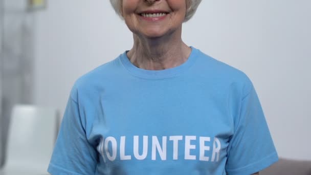 Senior vrouwelijke vrijwilliger op zoek naar camera en glimlachen, actieve gepensioneerde dame, hulp — Stockvideo