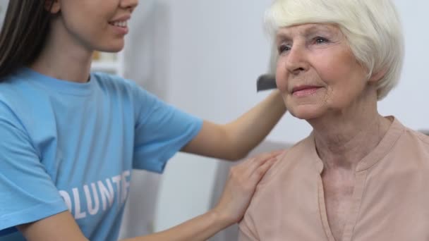 Mujer voluntaria peinando a una mujer anciana, trabajadora social visitando a una persona jubilada en casa — Vídeo de stock