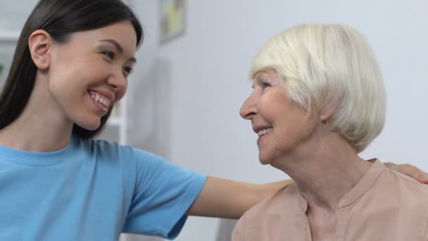 Friendly young lady smiling at happy senior lady, aid to seniors, family care — Stock Video