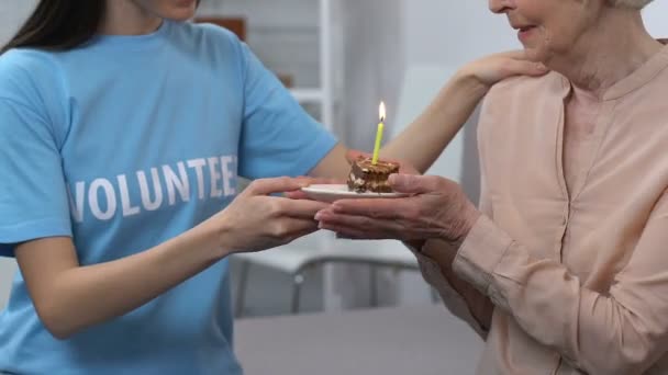 Joven voluntario y anciana celebrando cumpleaños, jubilado soplando vela — Vídeos de Stock