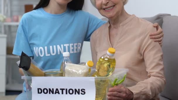 Glimlachend jong vrijwilliger en leeftijd vrouwelijke Holding doos met voedsel, sociale hulp — Stockvideo