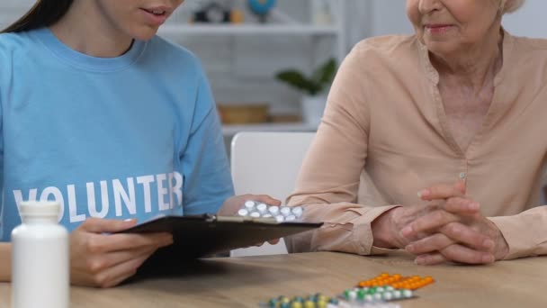 Mujer atenta voluntaria ayudando a anciana a elegir la medicina prescrita, cuidado — Vídeo de stock