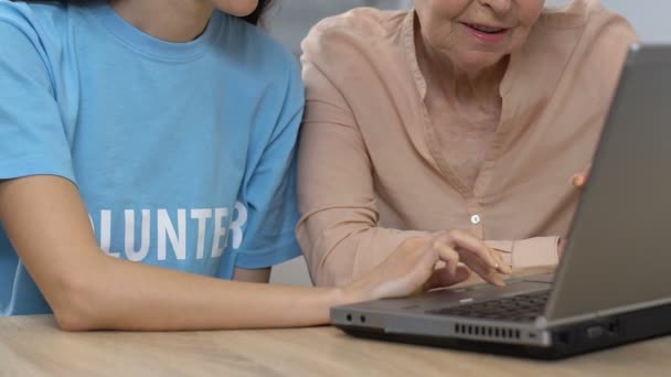 Женщина-волонтер показывает старушке программное обеспечение для ноутбука, планирует визит к врачу — стоковое видео