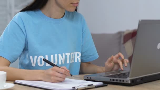 Jeune femme bénévole travaillant sur ordinateur portable et faire la liste, budget de planification — Video