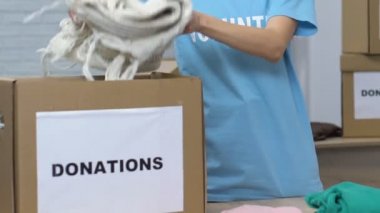 Genç bayan gönüllü bağışlar için kutusunda eşyalarını ambalaj, yoksul insanlar bakım