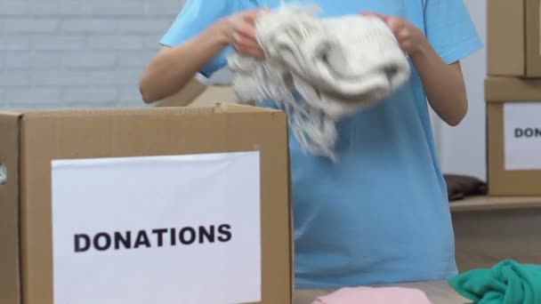 Kadın gönüllü bağışlar için kutuya giysi koyarak, hayır kurumu — Stok video