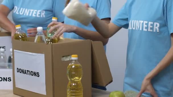 Group of volunteers packing food in donation boxes, working in social center — Stock Video