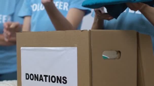 Volunteers packing clothes in box for donations, low-income families assistance — Stock Video