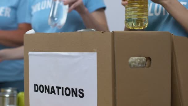 Grupo de voluntarios poniendo comestibles en caja de donaciones, organización benéfica — Vídeos de Stock
