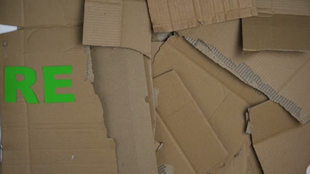 Geri dönüşüm kelime karton arka plan üzerinde yeşil harflerden yapılmış, gezegeni kurtarmak — Stok video