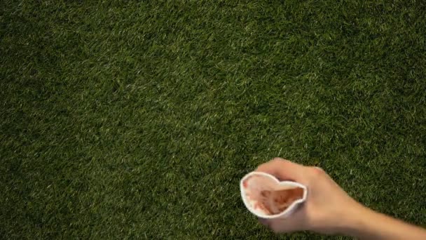 Mujer mano tirar taza de papel usado en la hierba vajilla desechable consumo excesivo — Vídeo de stock