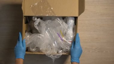 Kutudaki plastik çöpleri kontrol eden eldivenli istasyon çalışanı, atıkları azaltın