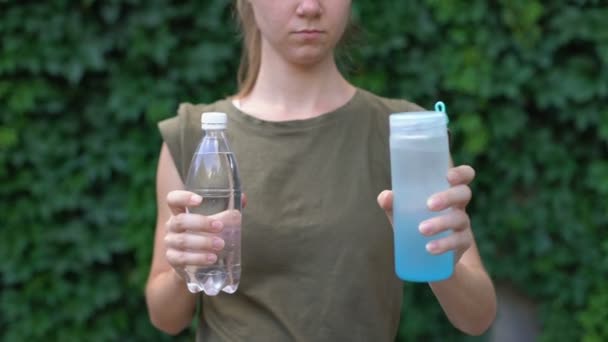 Kvinna väljer återanvändbar plastflaska istället för vanliga, ansvar — Stockvideo