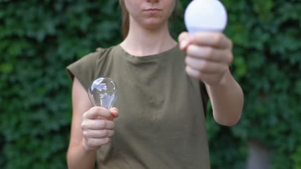 Женщина предпочитает светодиодную лампу лампочке, экономя природные ресурсы, окружающую среду — стоковое видео