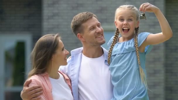 Padres alegres y niña sosteniendo la llave de la casa sonriendo en la cámara, compra — Vídeos de Stock