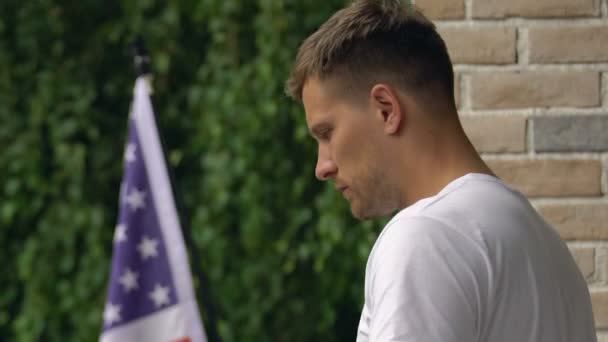 Depressief mannelijke staande huis Terras, Amerikaanse vlag buitenshuis, moeilijke keuze — Stockvideo