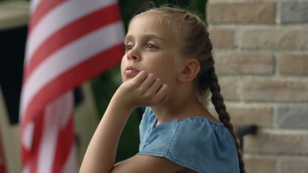 Ragazza triste mancante padre in piedi casa balcone, bandiera americana sfondo patriota — Video Stock