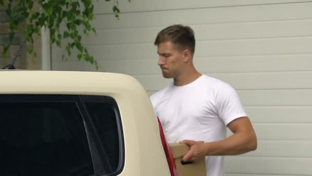 Joven poniendo caja de cartón en el maletero del coche, moviéndose de casa, reubicación — Vídeos de Stock