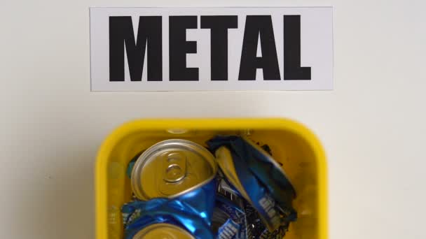 Pessoa colocando latas amassadas em recipiente de plástico perto de sinal de metal, reciclagem — Vídeo de Stock