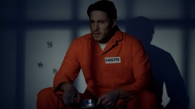 Mutsuz erkek mahkum gıda tabak, kötü koşullar ile oturan