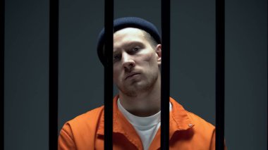 Hapishane parmaklıkları arkasında kameraya bakan korkmuş yüzü ile tehlikeli suçlu